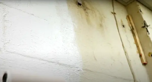 Roller painting a basement wall with regular paint will not stop a leaking wall as proven by the old paint. Waterproofing paint will force the water to collect at the bottom of the wall and will seep out through the floor.